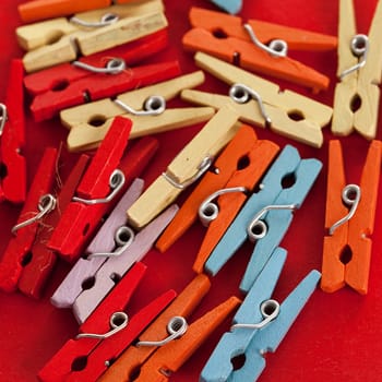 Closeup image of little colorful office clothespins on a red background