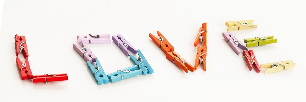 Love from little colorful office clothespins isolated on a white table