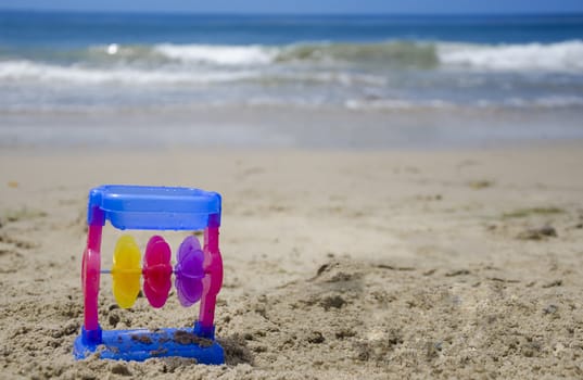Colorful child's toy on a beach's sand by the ocean