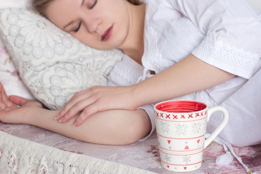 beautiful blond woman awaking with cup of coffee at bedroom