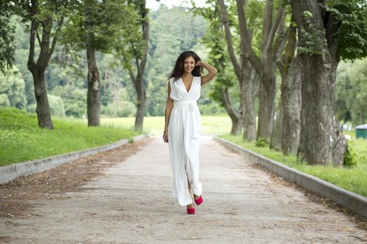 Beautiful young woman walking on the summer park