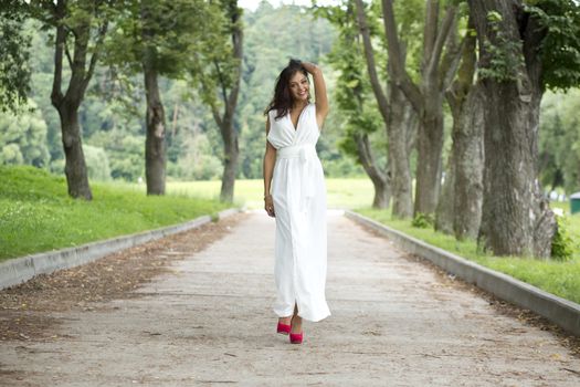 Beautiful young woman walking on the summer park