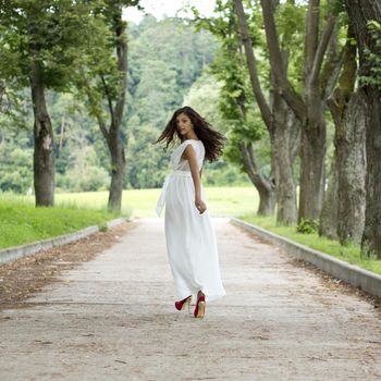 Beautiful young woman walking on the summer park