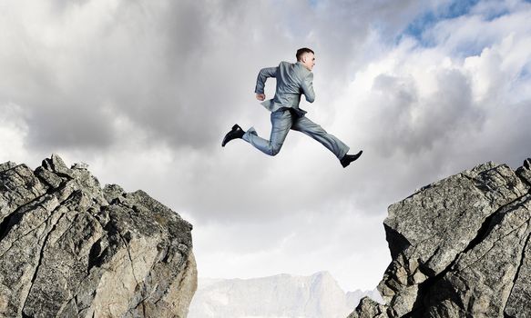 Image of young businessman jumping over gap