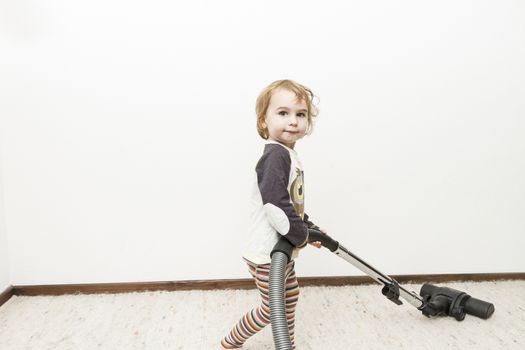 cute child doing household chore with vacuum cleaner