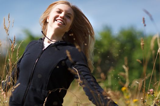 Young happy girl of twenty running in the field and laughing