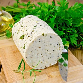 Homemade cheese with herbs and spices, knife, parsley, rosemary, vegetable oil in a bottle on a wooden board