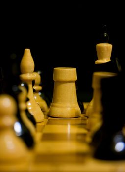 white chess bishop surrounded by black chess pieces on a chessboard