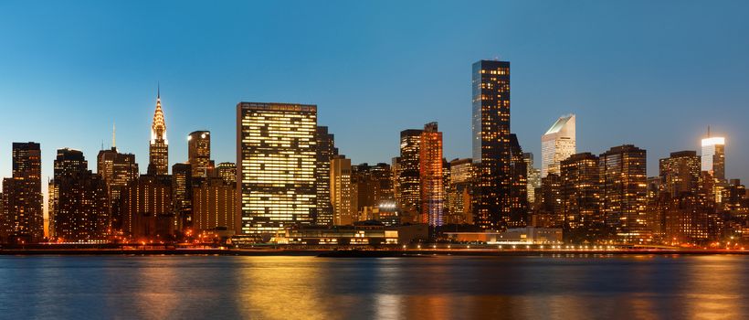 Manhattan. Late evening New York City skyline panorama with lights and reflections.