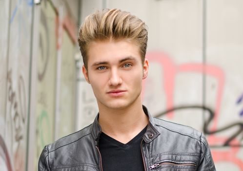 Head shot of handsome blond young man, outdoors looking in camera