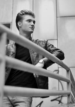 Handsome blond haired young man on metal railing, black and white shot