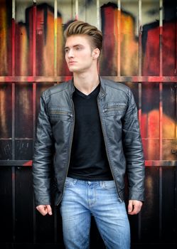 Attractive blond haired young man standing against graffiti wall