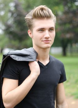 Attractive blond young man outdoors in a park, smiling