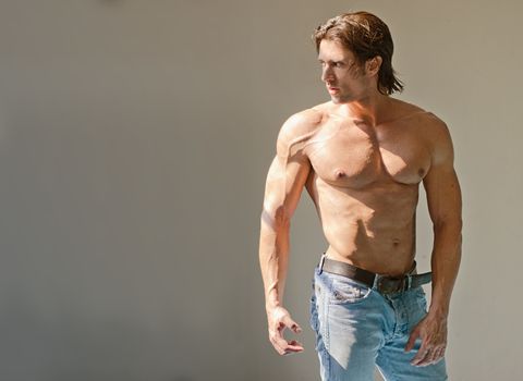 Handsome muscular man shirtless wearing jeans on grey background