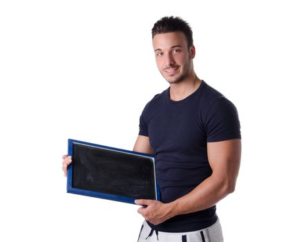 Smiling young man holding and showing empty blackboard and looking in camera