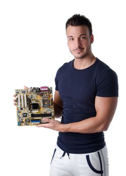 Smiling young man holding and showing computer motherboard and looking in camera