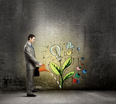 Image of businessman watering sprout with can