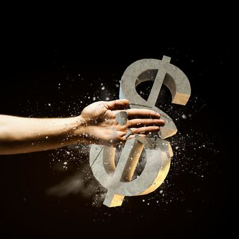 Close up image of human hand breaking dollar stone symbol