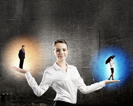 Image of businesswoman holding business persons in miniature on palms