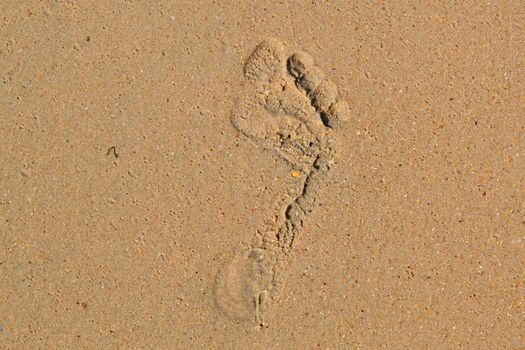 Trace of a bare foot of the person on sand.