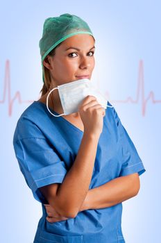 Young female surgeon with scrubs, holding a face mask with a EKG graph behind her