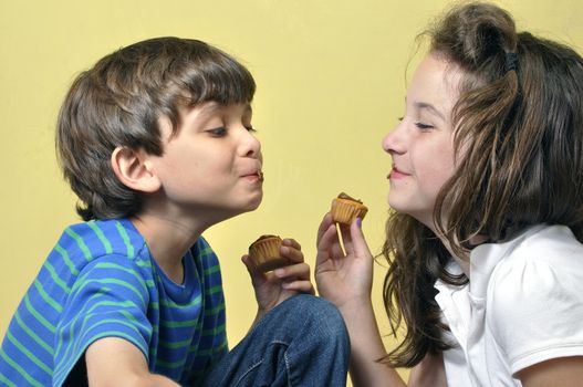 Little boy and girl have fun acting silly while eating cupcakes