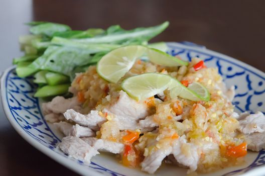 asian food ,  pork served with chili sauce ,  fresh lime and kale on dish