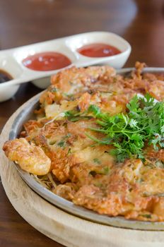 close up crispy omelet and  fresh vegetable served with tomato sauce and black sauce