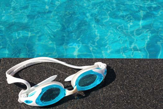 Blue swimming goggles on swimming pool background