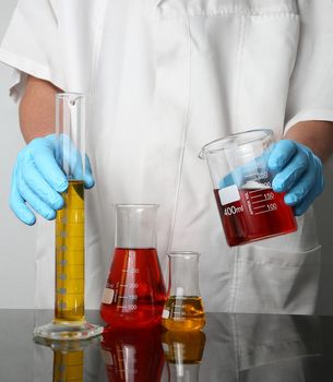 Laboratory Glassware with fluids and gloved hands