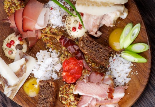 Arrangement of Various Uncooked, Smoked and Boiled Ham with Mustard, Salt, Pepper, Brown Bread and Spices closeup on Wooden Plate. Top View