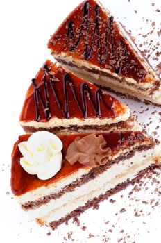 Three Slices of Delicious Cake with Glazed Cream and Grated Chocolate closeup on white background