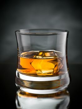 One glass of whisky on the rocks on black background