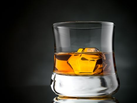 One glass of whisky on the rocks on black background