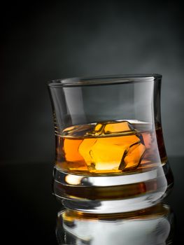 One glass of whisky on the rocks on black background