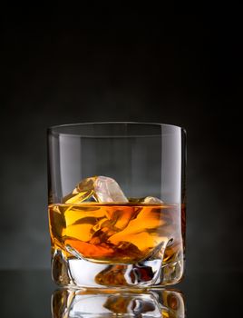 One glass of whisky on the rocks on black background