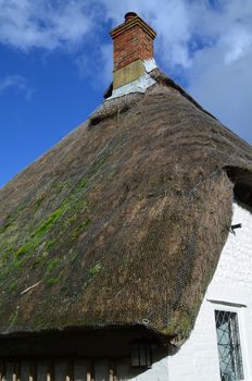 English country cottage with its thatched roof in need of repair.