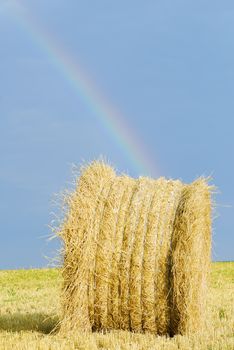 straw bale under stormy sky and rainbow