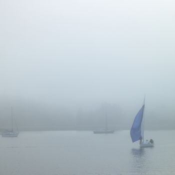 Boats on the water during a foggy day.
