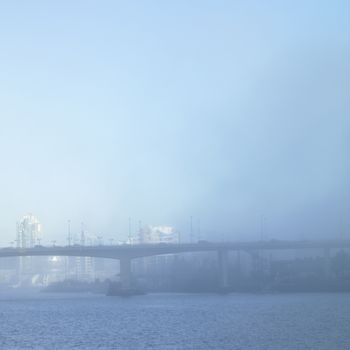 Bridge and cityscape on a foggy day.
