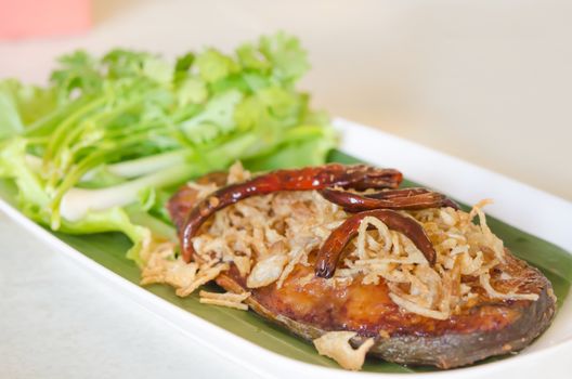 Fried pickled fish , onion  and chili served  with fresh vegetable on dish