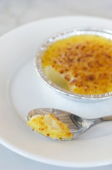 Sweet caramelized custard ,  creme brulee on silver spoon