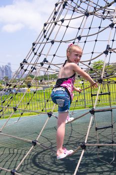 Girl climbing on rope ladder against sky