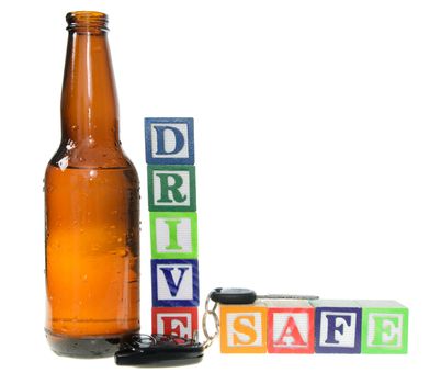 Letter blocks spelling drive safe with a beer bottle and keys. Isolated on a white background