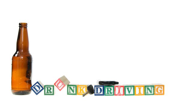 Letter blocks spelling drunk driving with keys and a beer bottle. Isolated on a white background.