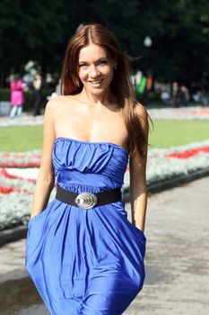 Beautiful young woman walking on the summer park