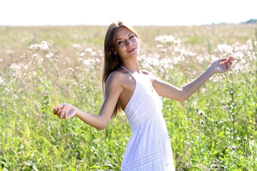 Young woman in summer dress walking on a meadow