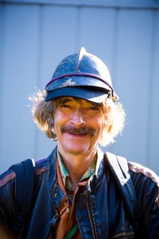 A man wears some interesting clothes including multiple layers and a hat with a helmet.