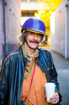 A man wears some interesting clothes including multiple layers and a hat with a helmet.