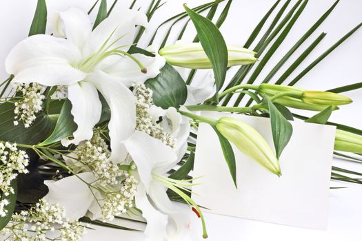 White lily flowers and post card over white background